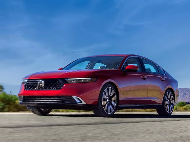 Red sedan car driving on a road.