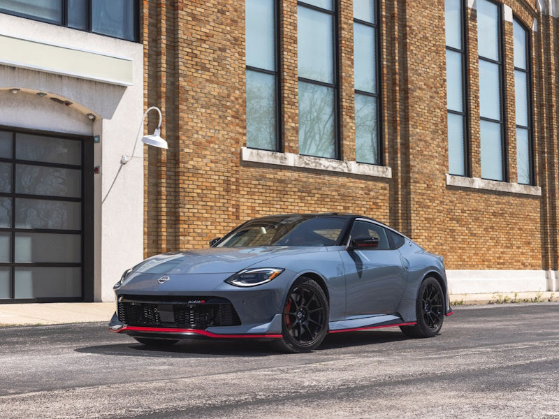 Blue sports car parked in front of a brick building.
