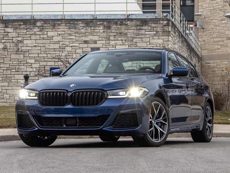 Blue BMW sedan parked in front of a brick building.