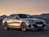 Silver BMW sedan parked on a road with mountains in the background.