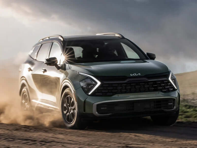 Green SUV driving on a dirt road.